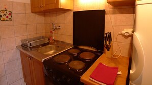 A compact kitchen with a stove, sink, and a microwave. - Apartment for two Persons With Swimming Pool Near the Beach (Medulin)