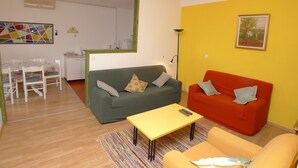 A living room with a green sofa, a red sofa, and a yellow table. There is a painting on the wall and a lamp. - Apartment for six Persons With 3 Bedrooms and Partial sea View (Medulin)