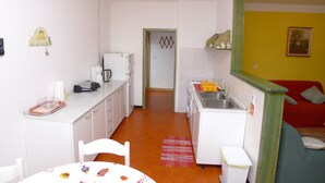 A compact kitchen with white appliances, a dining area with a table and chairs, and a red sofa in the living area. - Apartment for six Persons With 3 Bedrooms and Partial sea View (Medulin)