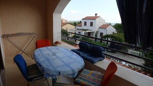 A balcony with a table and chairs, a drying rack, and a view of buildings. - Apartment for six Persons With 3 Bedrooms and Partial sea View (Medulin)