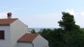 A two-story building with a red-tiled roof, a chimney, and a view of the sea. - Apartment for six Persons With 3 Bedrooms and Partial sea View (Medulin)