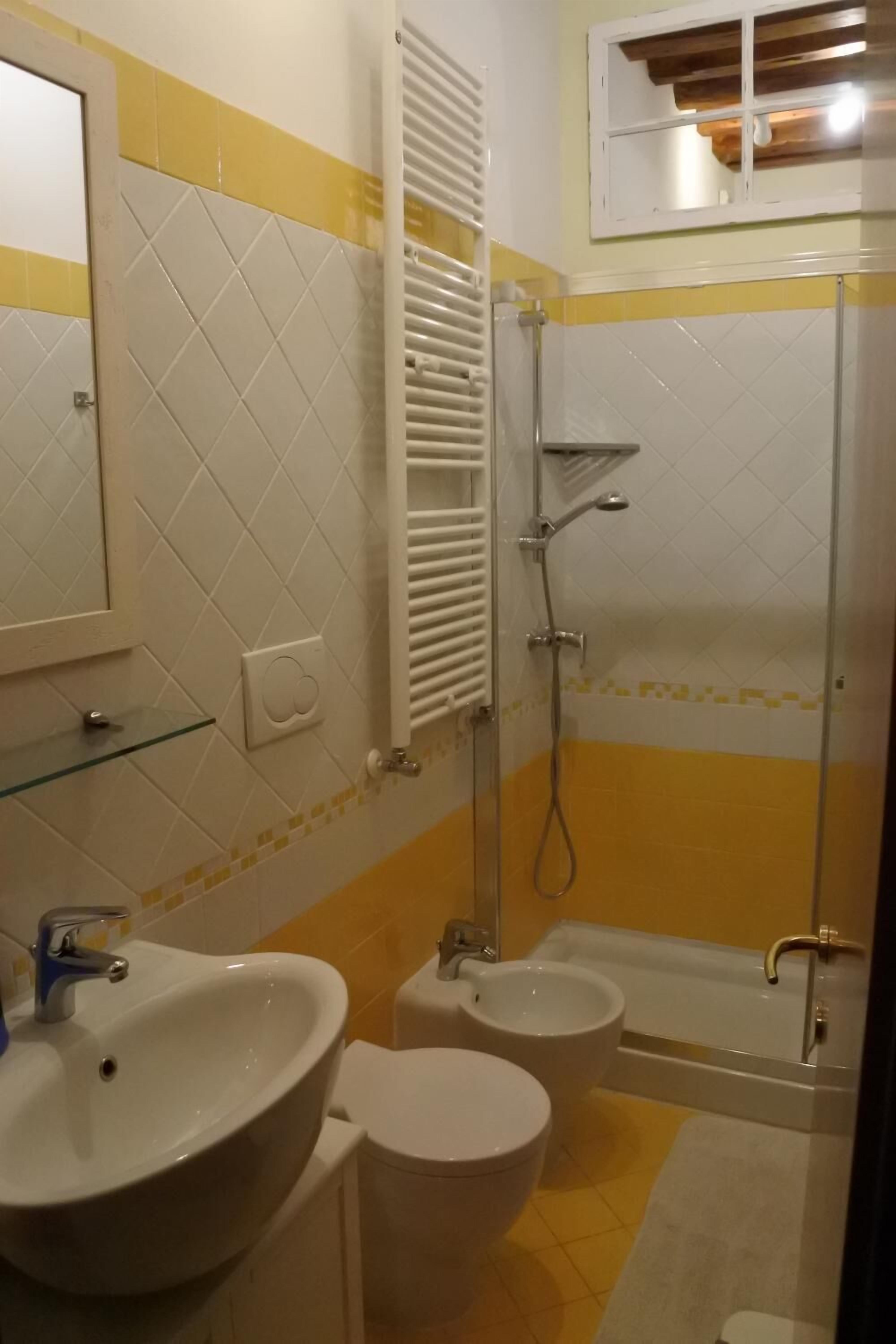 A bathroom with a sink, toilet, bidet, and shower.