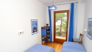 A room with two beds, a desk, and a balcony with blue curtains. - Apartment for six Persons With Three Bedrooms and Internet (Medulin)