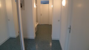 A narrow hallway with a door at the end, a small bench, and a light fixture on the wall. - Apartment for six Persons With Three Bedrooms and Internet (Medulin)