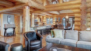 A log cabin interior with a dining area, kitchen, and seating space. - Highlands Treehouse with Shuffleboard & Private Hot Tub! Golf Course & Mountain Views! (Breckenridge)