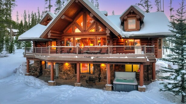 A log cabin with a balcony, stone foundation, and a hot tub. - Highlands Treehouse with Shuffleboard & Private Hot Tub! Golf Course & Mountain Views! (Breckenridge)