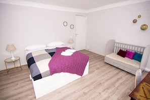 A bedroom with a bed, bedside tables, a sofa, and a door.
