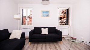 Ein Wohnzimmer mit einer schwarzen Couch, einem Glastisch und einer weißen Lampe.