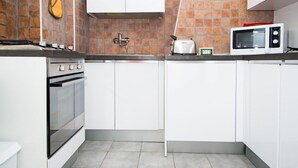 Eine kleine Küche mit weißen Schränken, einem Gasherd, einer Mikrowelle und einem Toaster.