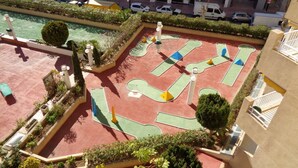 Un terrain de sport sur le toit, avec une piscine, entouré de verdure et de bâtiments.