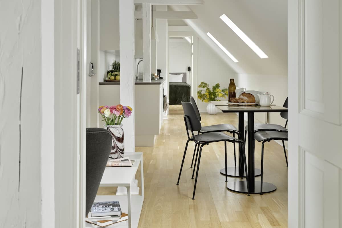 Un espace de vie moderne, à aire ouverte, comprenant un coin repas, une cuisine et une chambre visible.