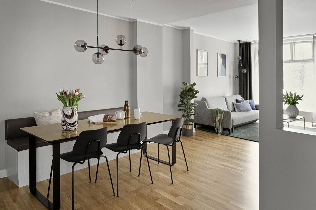 Un salon moderne avec un coin repas, comprenant un plancher en bois, un canapé, une table basse et une table à manger avec des chaises.