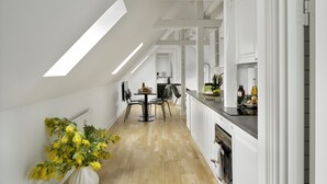 Una cocina moderna con armarios blancos, un comedor con mesa y sillas, y un ventanal que proporciona luz natural.