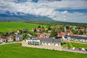A residential area with houses, a large building, and a mountain range in the background. - Penzión Čerešnový Sad (Mengusovce)
