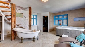 A bathroom with a freestanding bathtub, a wooden staircase, and a seating area with a hot tub. - Penzión Čerešnový Sad (Mengusovce)