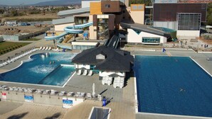 A modern hotel with multiple swimming pools, a water slide, and a mountain backdrop. - Penzión Čerešnový Sad (Mengusovce)