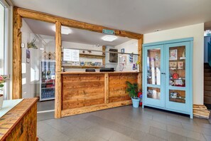 A reception area with a wooden reception desk, a blue cabinet with glass doors, and a potted plant. - Penzión Čerešnový Sad (Mengusovce)