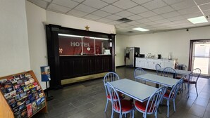 A hotel reception area with a counter, a display of brochures, and a seating area with tables and chairs. - Super 7 Inn (Midland)