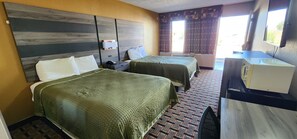 A hotel room with two beds, a desk with a sink, and a television. - Super 7 Inn (Midland)