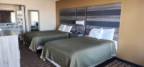 A hotel room with two beds, a bathroom, and a mirror.