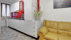 Ein Zimmer mit Küchenzeile, einer Couch und einem Gemälde an der Wand.