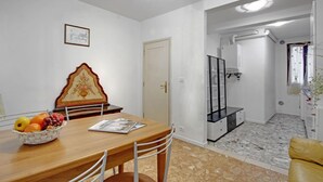 Ein Essbereich mit einem Holztisch, Stühlen, einer Obstschale und einem gerahmten Bild an der Wand.