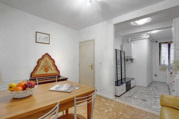 Un comedor con una mesa de madera, sillas, un frutero y un cuadro en la pared.