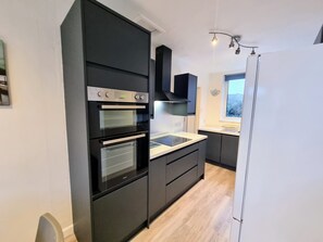 A modern kitchen with built-in appliances, a window, and a view of the outdoors. - Filton House (Bristol)