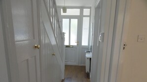 A narrow hallway with white doors and a window at the end. - Filton House (Bristol)