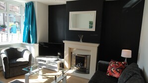 A living room with a fireplace, a sofa, a chair, and a glass coffee table. - Filton House (Bristol)