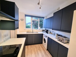 A compact kitchen with a built-in washing machine, a microwave, and a toaster. - Filton House (Bristol)