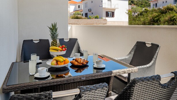 Een balkon met een ontbijttafel, compleet met fruit, gebak en drankjes.