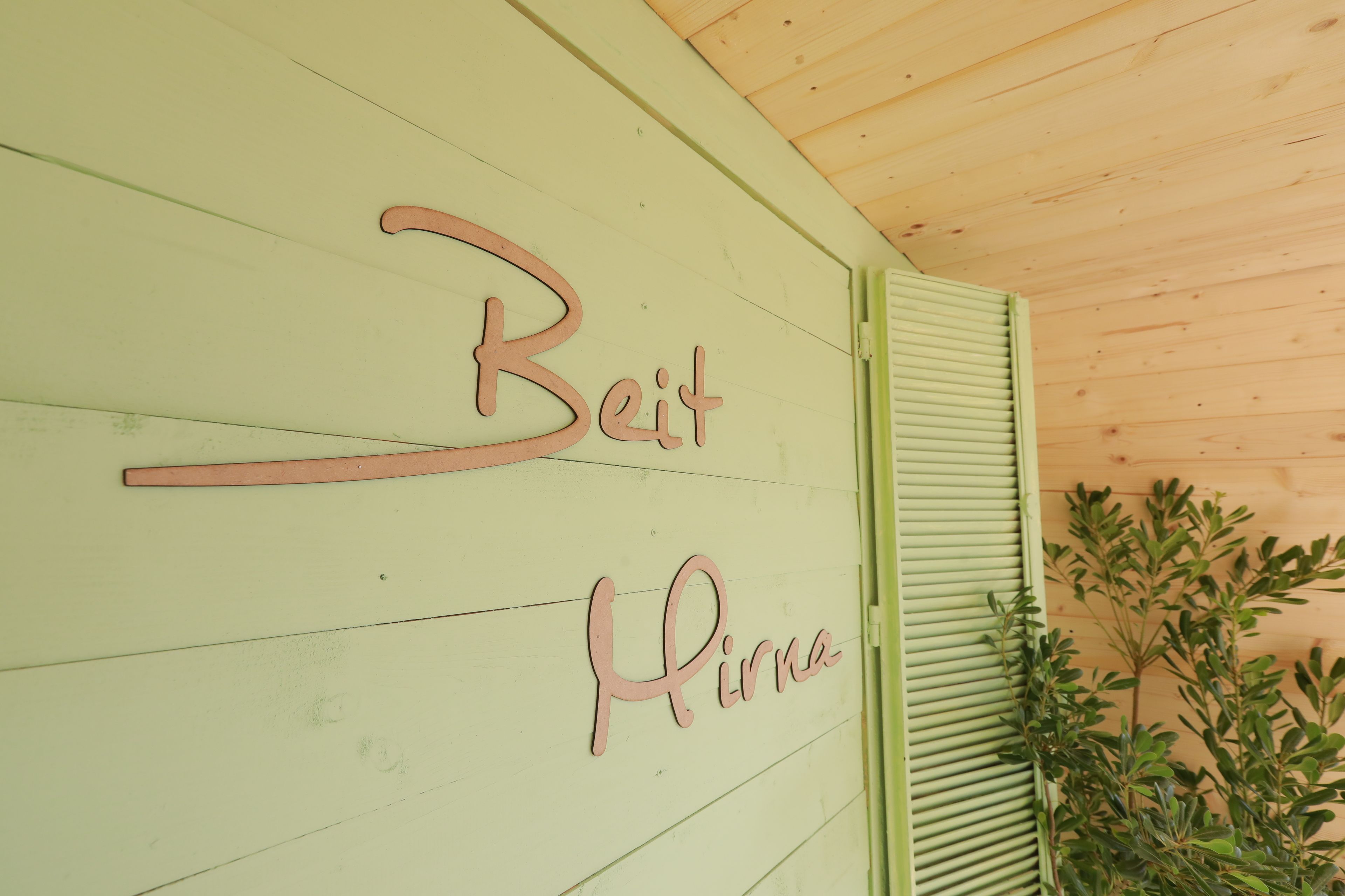 A wooden wall with the words "Beit" and "Hirna" in pink letters.