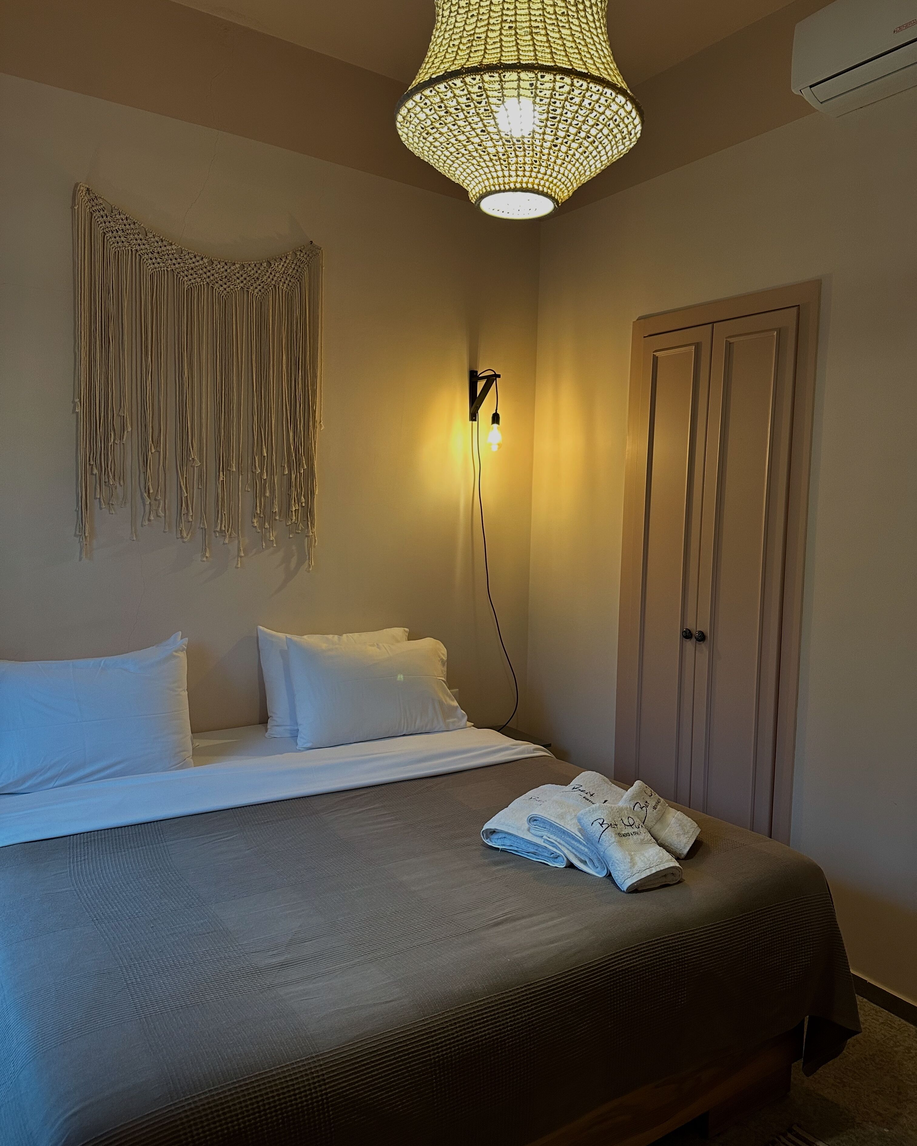 Une chambre d’hôtel comprenant un lit, un luminaire fixé au mur, une armoire et un élément décoratif mural.