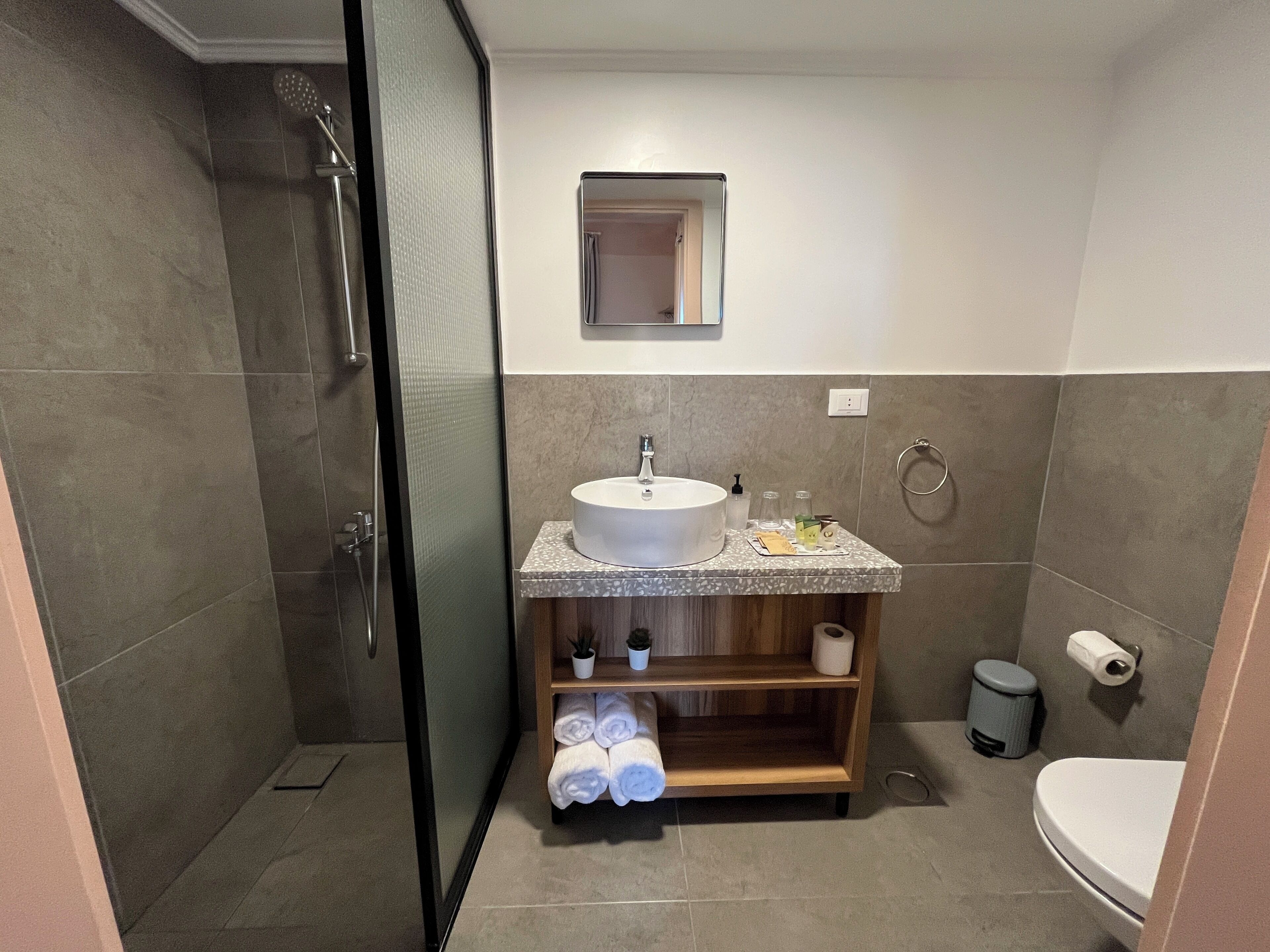 Ein modernes Badezimmer mit einer Duschkabine, einem Waschbecken mit Marmorplatte und einer Toilette.