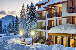 A multi-story building with balconies, surrounded by snow-covered trees and a snowy landscape. - Mountain Lake Hotel (Smolyan)
