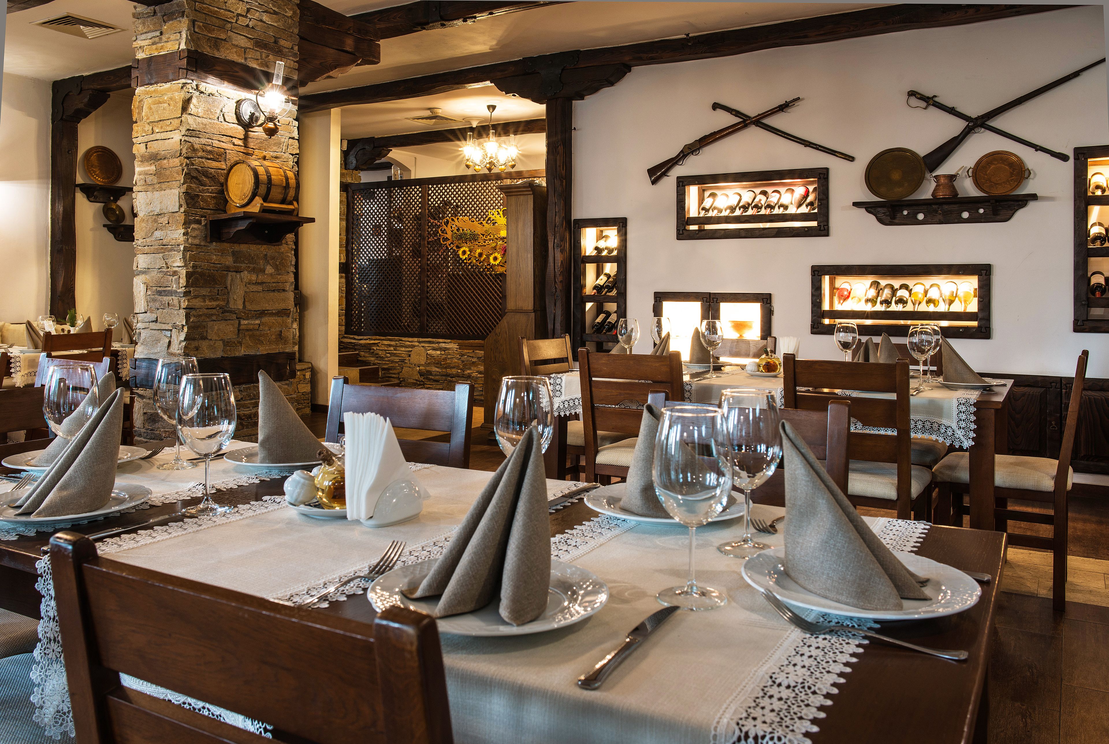 A dining area with tables set for a meal, featuring neatly folded napkins, wine glasses, and cutlery.