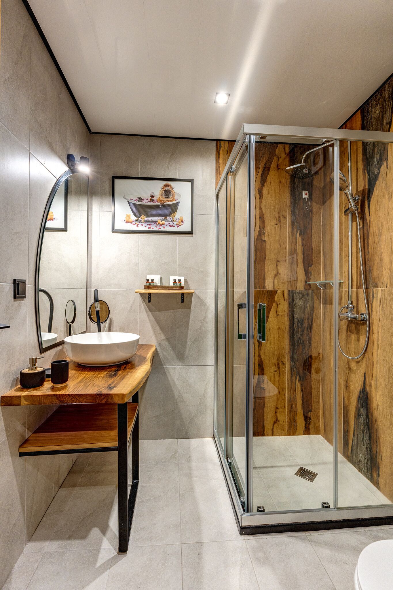Un baño moderno con tocador de madera, ducha con cerramiento de vidrio y un espejo grande.