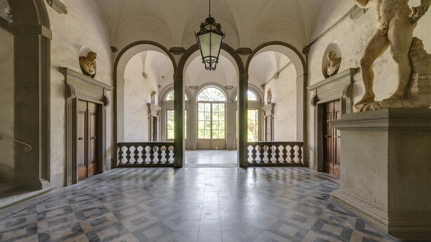 Un vaste hall doté d’un sol à motifs, de voûtes en arc et de statues classiques.