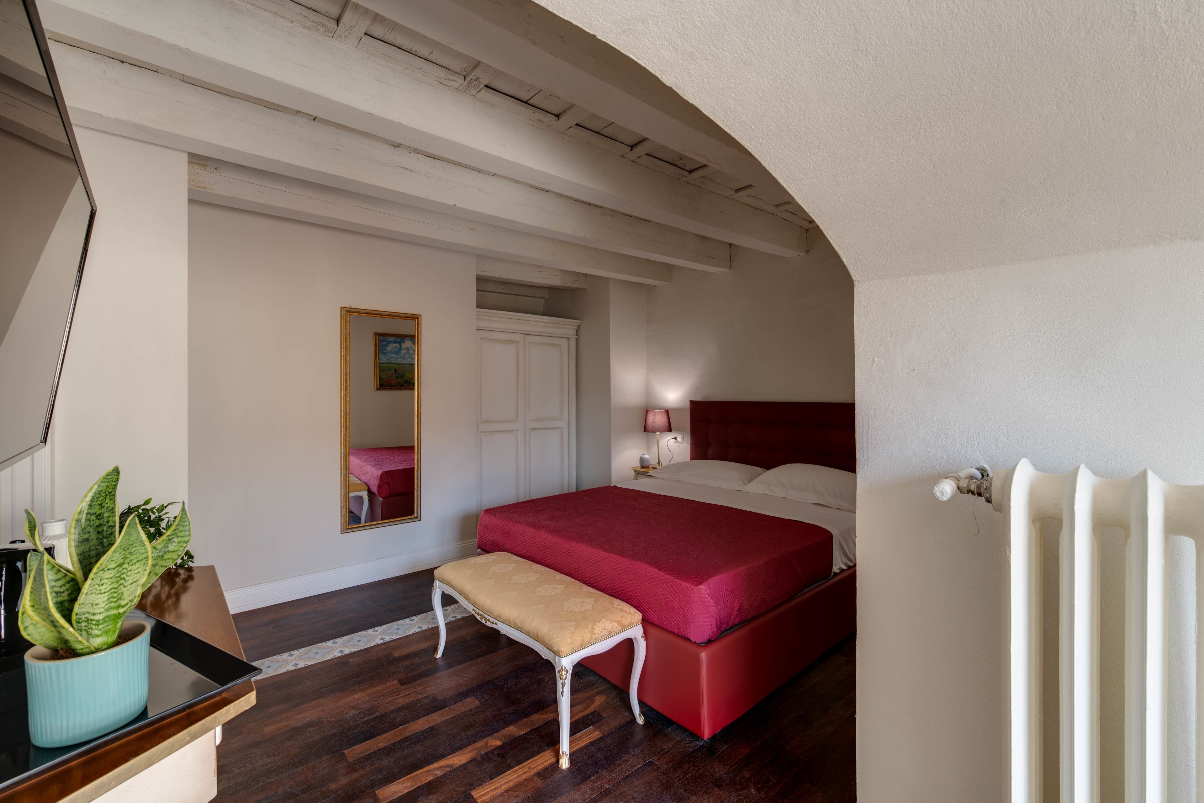 Une chambre à coucher avec un lit, une table de chevet, une lampe et une plante en pot.
