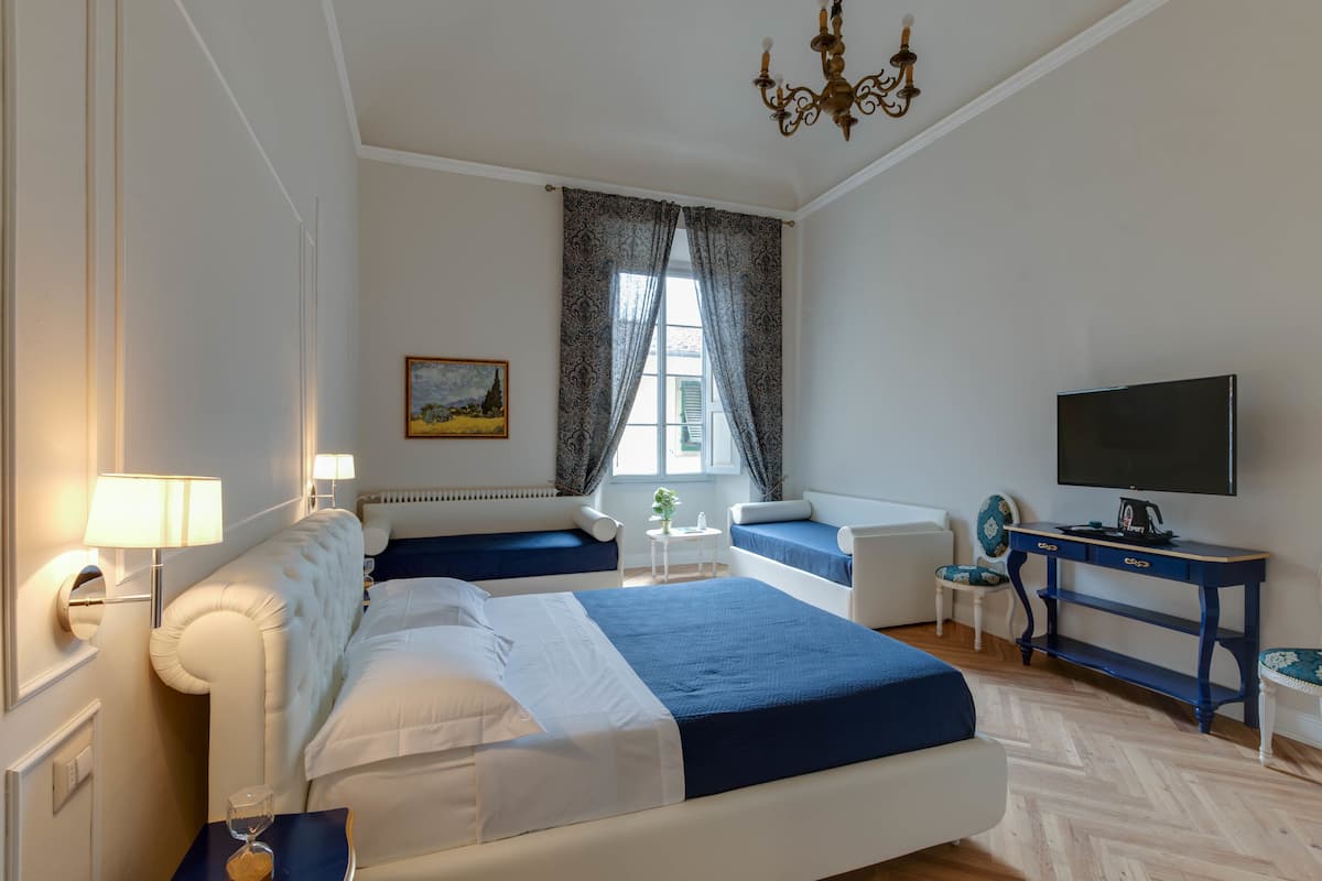 Een hotelkamer met een groot bed, een bureau, een televisie en een raam met gordijnen.