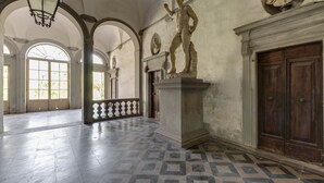 Un vaste hall doté d’un sol carrelé, de fenêtres en arc de cercle et de statues classiques.