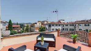 Une terrasse sur le toit, aménagée avec des meubles en osier, des plantes en pot et offrant une vue dégagée sur le paysage urbain.