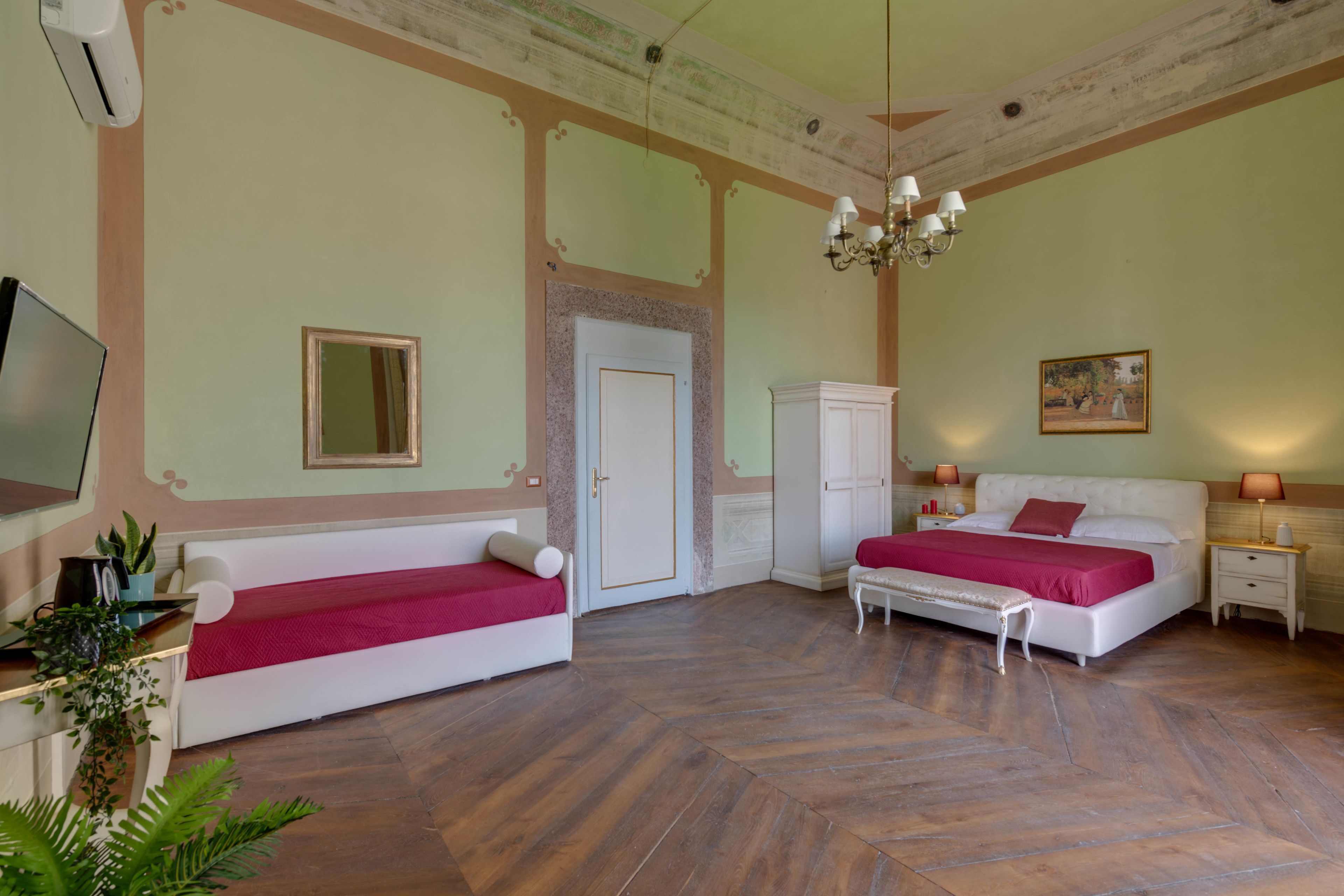 Une chambre avec deux lits, une armoire, un téléviseur et un lustre.