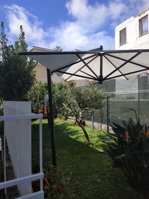 Ein Garten mit weißem Zaun, einer Pergola und verschiedenen Pflanzen.