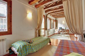 A bedroom with a bed, a desk, and a window.