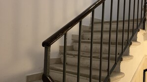 A staircase with a wooden handrail and metal balusters, leading to a landing with a door. - Grimaldi Apartments - Ca Orlina (Venice)