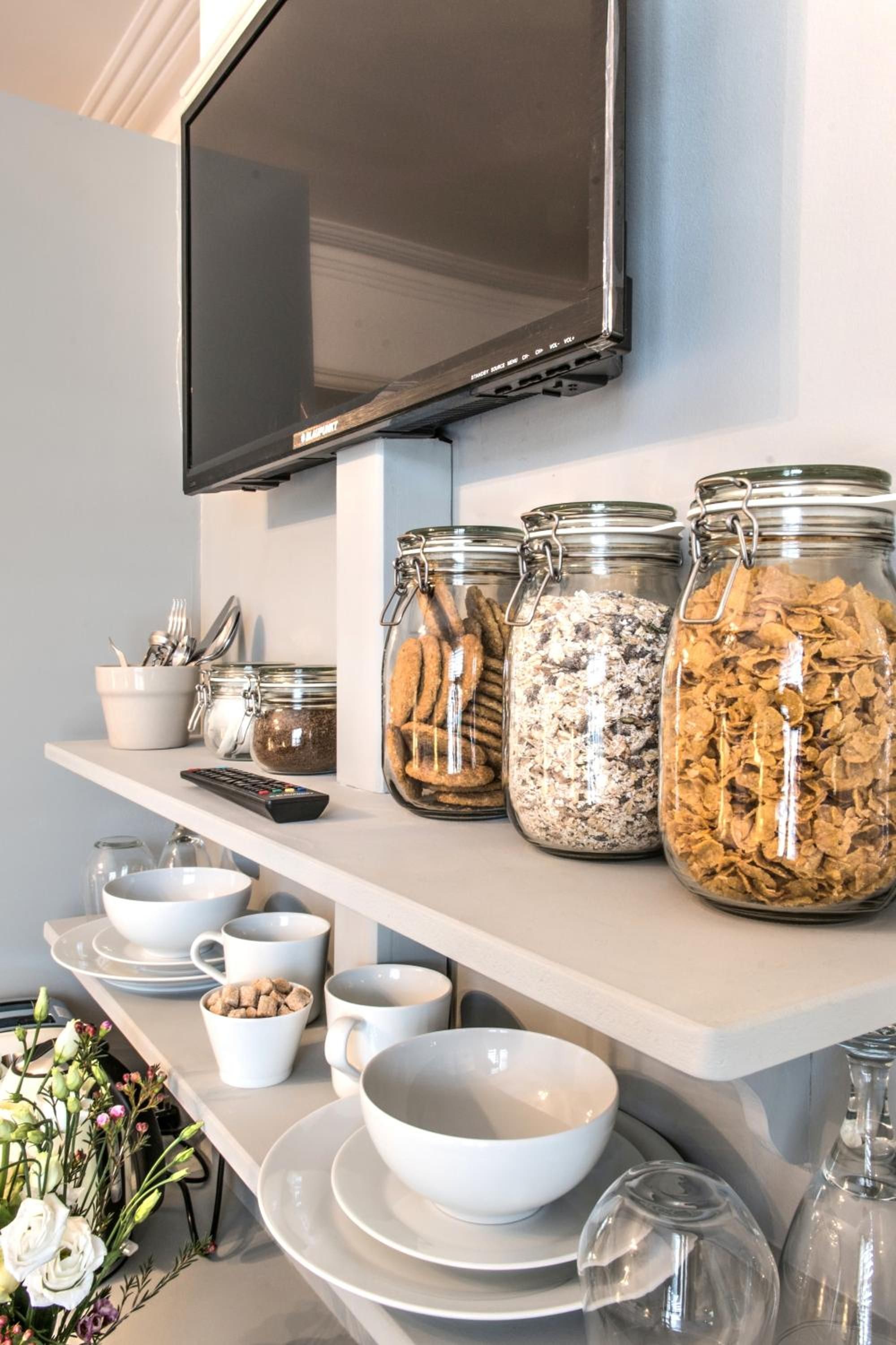 Una barra de desayuno con botes de cereales, tazones y un control remoto.