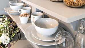 A breakfast bar with jars of cereal, bowls, and a remote control. - April House Weybridge - Boutique Guesthouse (Weybridge)