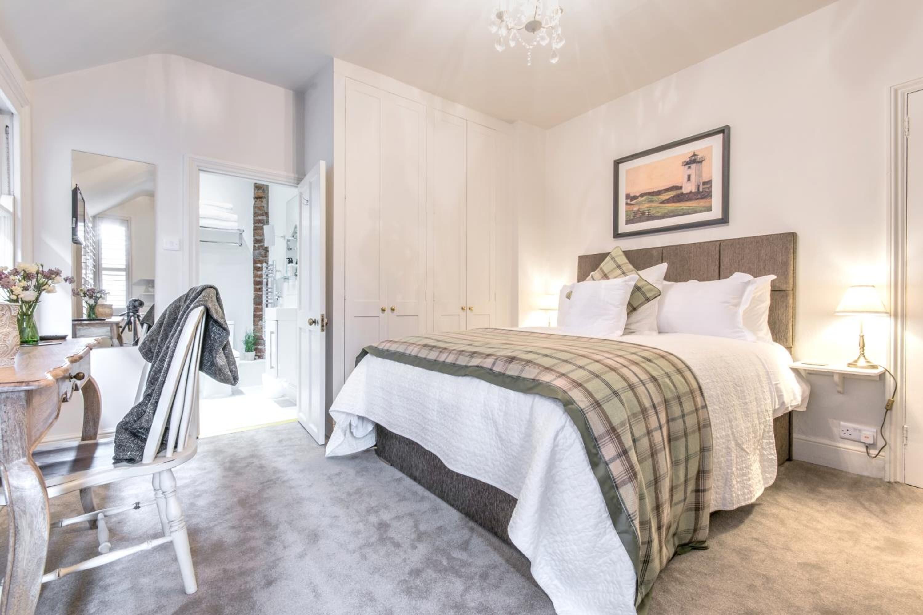 A bedroom with a bed, bedside table, and a painting on the wall.
